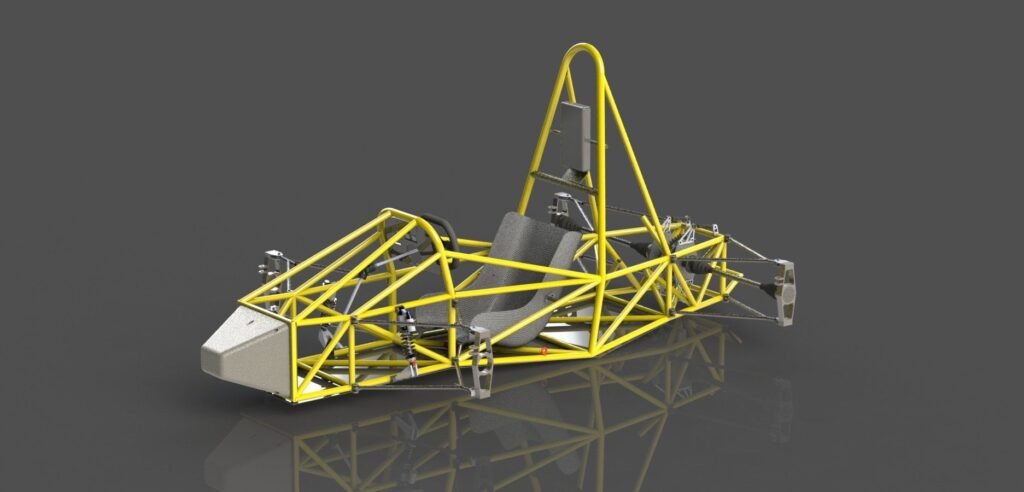 A imagem apresenta a carcaça de um veículo de competição, com partes em amarelo e o banco em cinza. O fundo é cinza e espelhado.