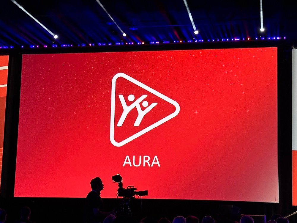 A imagem mostra um telão com o logo da AURA, a IA da SOLIDWORKS.